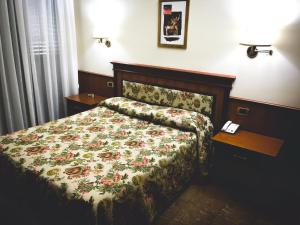 1 dormitorio con 1 cama con colcha de flores en Hotel Malaga en Avellino