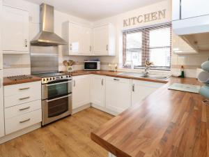 a kitchen with white cabinets and a wooden floor at The Haybarn in West Bradenham