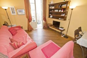 een woonkamer met een roze bank en een televisie bij PROMENADE HOLIDAY - GRIMALDI CITY CENTER in Nice