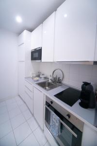 a kitchen with white cabinets and a sink at Bliss Lisbon Apartments - Bairro Alto in Lisbon