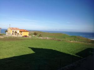 uma casa no topo de um campo verde com o oceano em Apartamentos Santa Justa em Ubiarco