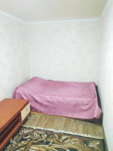 una piccola camera con letto rosa e cassettiera di Двухкомнатная квартира в центре a Okhtyrka