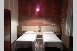 um quarto com três camas contra uma parede de tijolos em Villa Biagi quadrilocale la Conchiglia em San Vincenzo