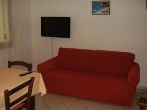 a living room with a red couch and a television at Casa Giovanna in Porto Pino