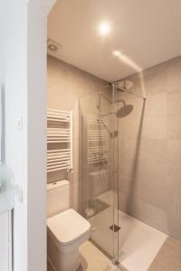 uma casa de banho com um WC e uma cabina de duche em vidro. em Cituspace Arturo Soria em Madri