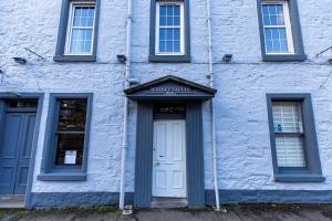 um edifício azul com uma porta branca e janelas em The Whisky Vaults em Oban