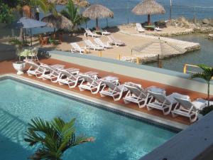 a swimming pool with lounge chairs and a beach at Pipers Cove Resort in Runaway Bay