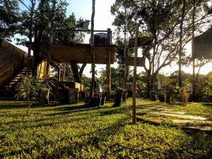 a tree house with a swing in the grass at 4 Elementos Guest House in Arraial d'Ajuda