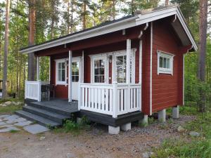 a red tiny house with a porch and a deck at Nestorin maja in Puumala