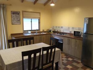 a kitchen with a table with chairs and a refrigerator at Cabañas Dahue in Valdivia