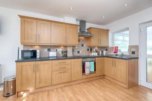 a kitchen with wooden cabinets and a microwave at Pleasant Stay in Swansea - TV in Every Bedroom! in Swansea