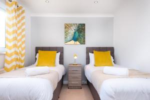 2 camas individuales en una habitación con almohadas amarillas en Contractor Stay - Parking - En-suites - TVs, en Swansea