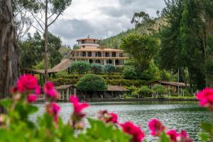 a large house on top of a lake with pink flowers at Fundo El Chocho in Cajamarca