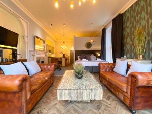 uma sala de estar com sofás de couro e uma cama em The Deakin at Claremont Serviced Apartments em Leeds