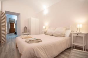 1 dormitorio con 1 cama blanca grande y toallas. en Apartamento nuevo Casco Antiguo AT Postigo 20, en Cáceres