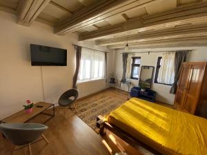 a bedroom with a yellow bed and a flat screen tv at SIM House & Barn in Săcele