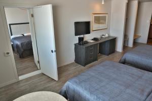 a hotel room with a bedroom with a bed and a mirror at Motel Castille in Roberval