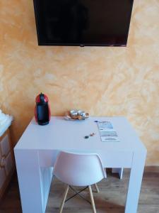 a white table with a chair and a tv on a wall at Hospedaje Menendez Pelayo in Santander