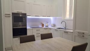 a kitchen with white cabinets and a table with chairs at Ivory Suite Valletta in Valletta