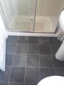 a bathroom with a shower and a tiled floor at Heart of Filey in Filey