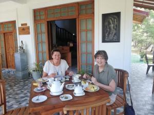 two women sitting at a wooden table with food at The European Gate - Anuradhapura in Anuradhapura
