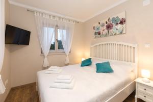a bedroom with a white bed with blue pillows at Villa Diamond - Muraj Krk in Kornić