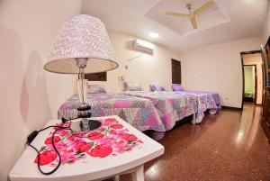 Habitación con 2 camas y mesa con lámpara. en Palmera Hotel CDE en Ciudad del Este
