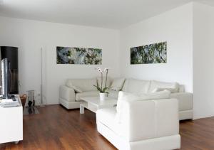 - un salon avec un mobilier blanc et deux peintures murales dans l'établissement Apartment Superior Parrot, à Zermatt