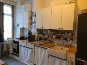 - une cuisine avec des placards blancs et un évier dans l'établissement Petit cocon lillois:Cheminée & jardin, à Lille