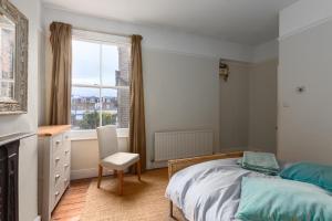 um quarto com uma cama, uma cadeira e uma janela em Wix's Lane em Londres