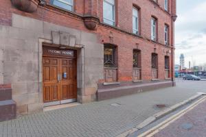 ein Backsteingebäude mit einer Holztür an einer Straße in der Unterkunft Cosy and modern apartment HEART OF BELFAST in Belfast