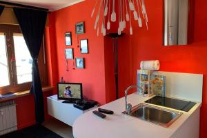 a kitchen with red walls and a sink and a counter at A 2 minuti dalle piste da sci e campo da golf. in Sestriere