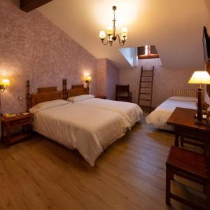 a bedroom with two beds and a chandelier at Hotel Las Cancelas in Ávila