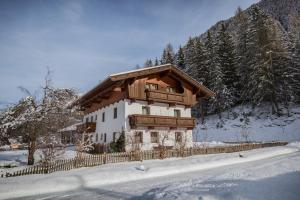 ein Haus mit einem Holzdach im Schnee in der Unterkunft Ferienheim Gabi in Neustift im Stubaital