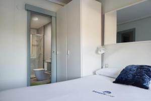 a bedroom with a white bed and a mirror at Marrubi - Basque Stay in San Sebastián