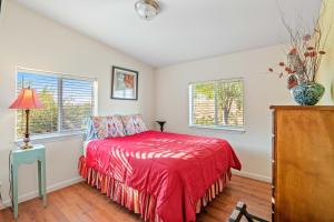 a bedroom with a red bed and two windows at Sirena Vineyard Resort - 3 Bedroom guest house in Paso Robles