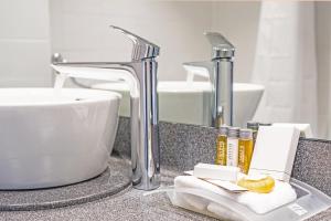 
a bathroom sink with a glass of water next to it at Holiday Inn Farnborough, an IHG Hotel in Farnborough
