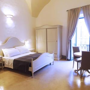1 dormitorio con 1 cama, mesa y sillas en Le Finestre Su Porta Carrese - Luxury Rooms & Suites, en Matino