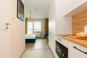 eine Küche mit weißen Schränken und ein Zimmer mit einem Bett in der Unterkunft Warsaw To Be - Golden Apartment in Warschau