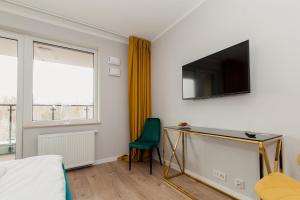 sypialnia z biurkiem i telewizorem na ścianie w obiekcie Warsaw To Be - Golden Apartment w Warszawie