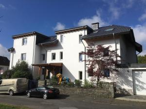 a white house with a car parked in front of it at Stadtvilla Intzeplatz - Apartment Föhr in Remscheid