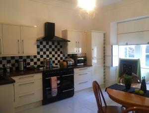 a kitchen with white cabinets and a black stove top oven at Dundee Beds in Dundee