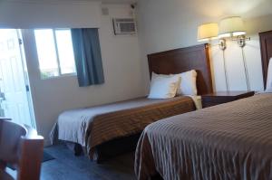 a hotel room with two beds and a window at Westward Inn & Suites in Langley