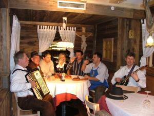 eine Gruppe von Menschen, die mit Instrumenten um einen Tisch sitzen in der Unterkunft Hotel Gurschler in St. Leonhard in Passeier