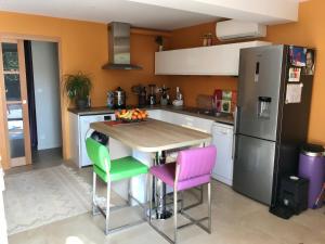 a kitchen with a table with four chairs and a refrigerator at Villa l’Ensoleillée in Roquefort-les-Pins