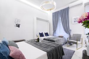 biała sypialnia z 2 łóżkami i krzesłem w obiekcie Roma Deluxe Apartments w Rzymie