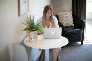 a woman sitting at a table with a laptop at Alpine Lake Motel in Taupo