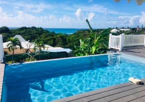 a blue swimming pool with a view of the ocean at VILLA TI PUNCH in Sainte-Anne