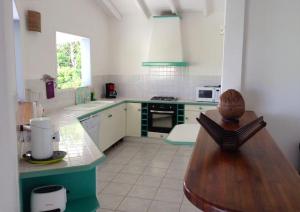 una cocina con armarios verdes y blancos y una mesa de madera. en VILLA TI PUNCH, en Sainte-Anne