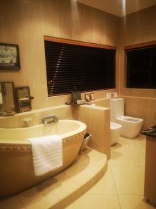 a bathroom with a tub and a toilet and a sink at Bristow Luxury Suites With Back Up Power and Free Wi-Fi in Roodepoort +16 photos